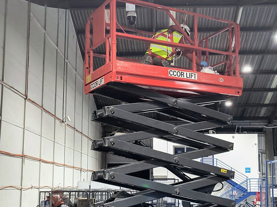 Técnico instalando una cámara de videovigilancia en altura dentro de una bodega industrial